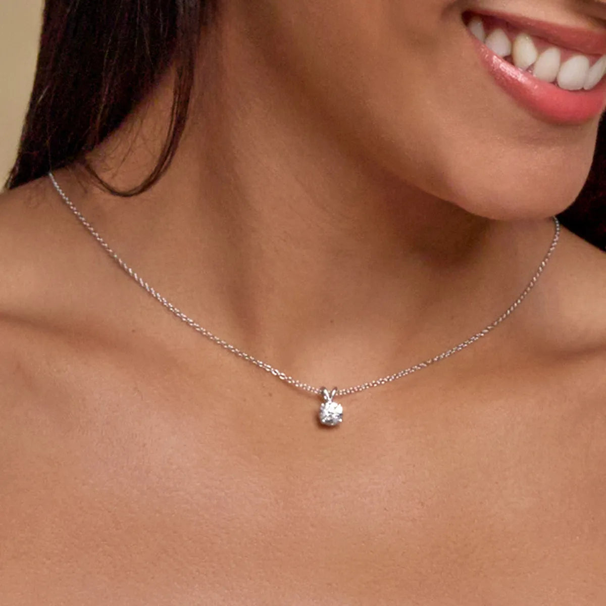 Close-up of a woman wearing a silver necklace with a pendant.